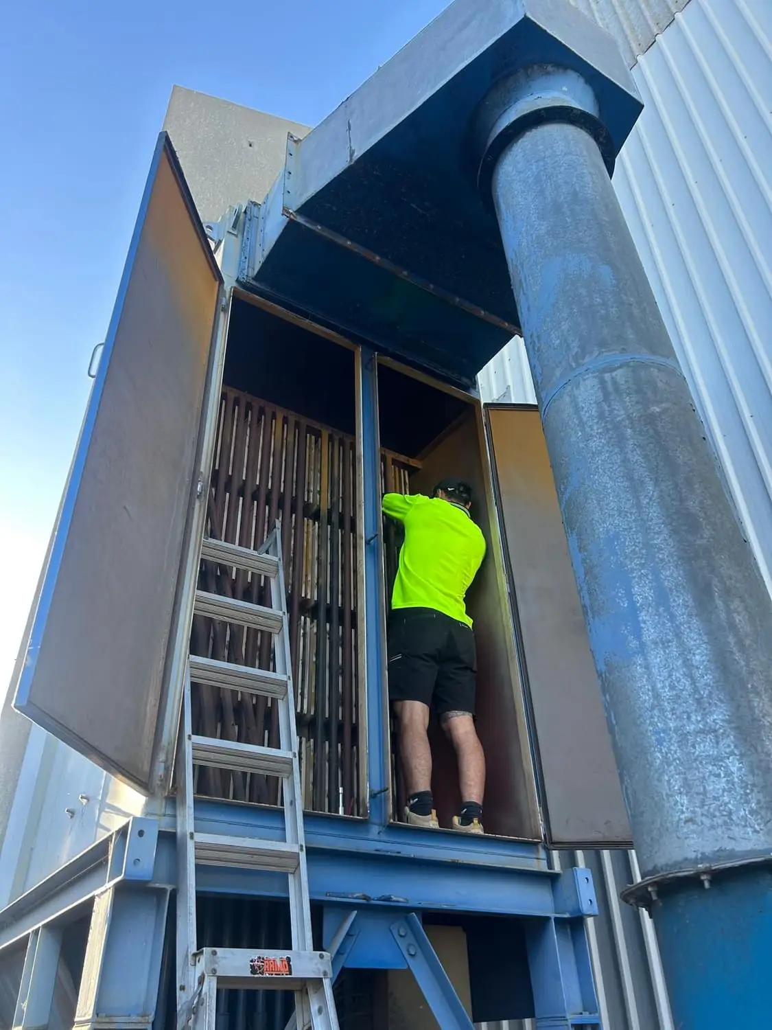 Aerobreeze technician working inside a commercial air handling unit, reached by ladder