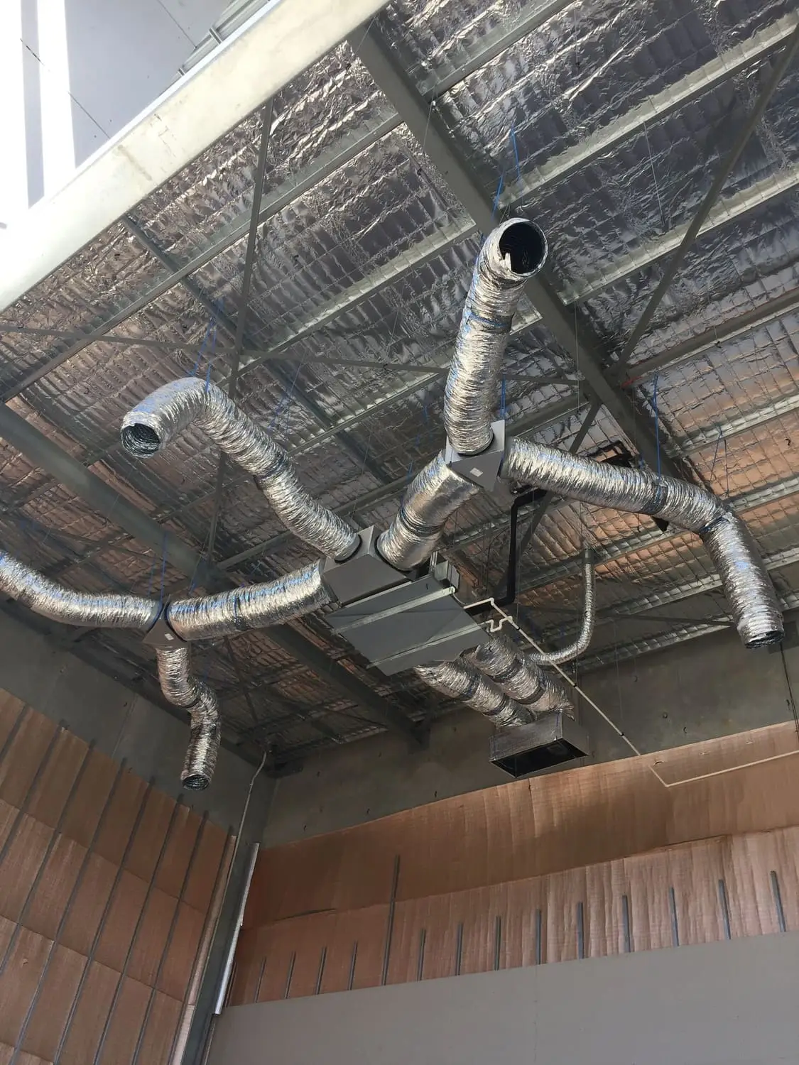 Insulated flexible ducting fanning out from a ceiling-mounted indoor unit in a commercial fit-out