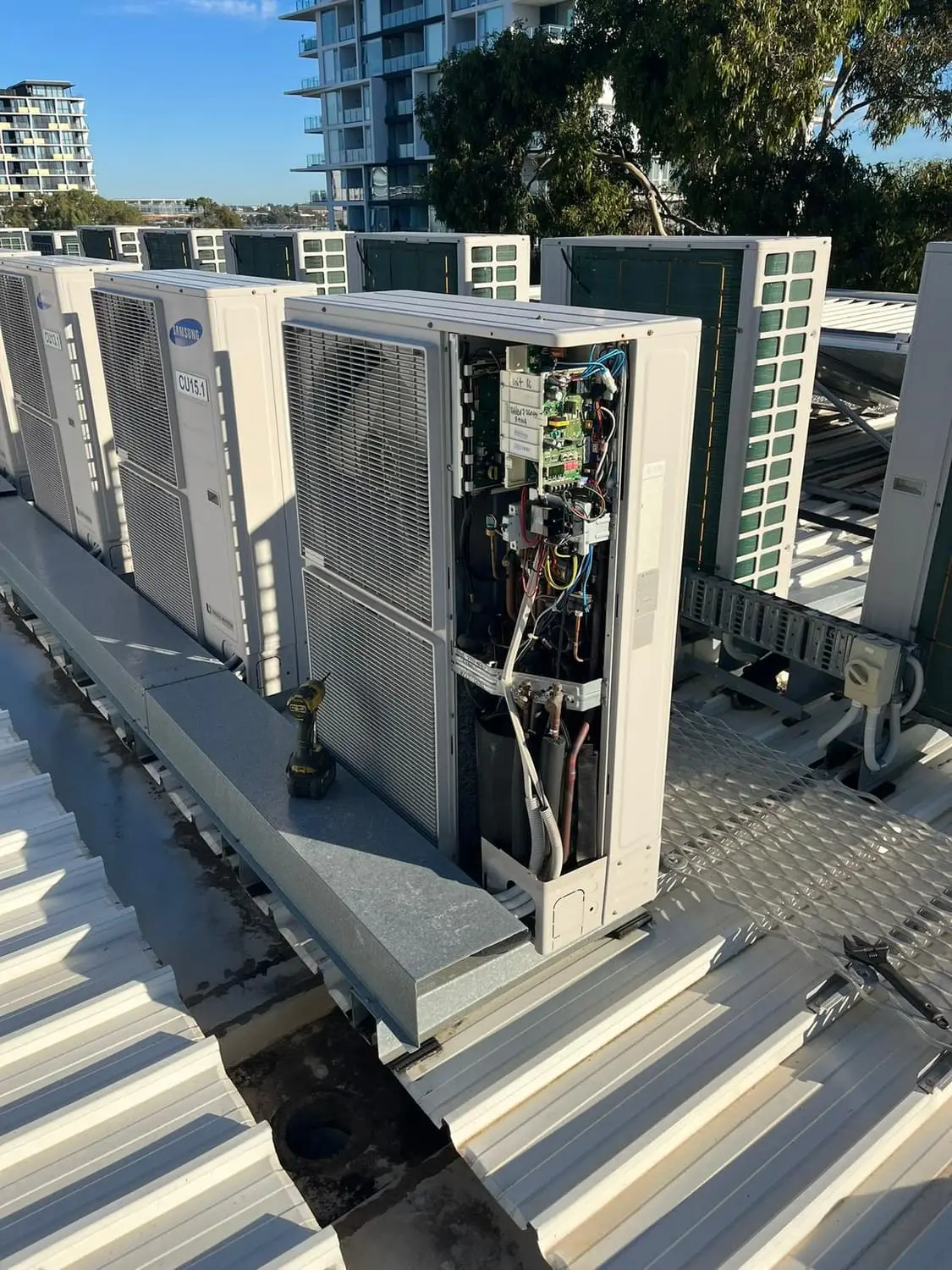A row of outdoor condensing units lined up on a commercial roof