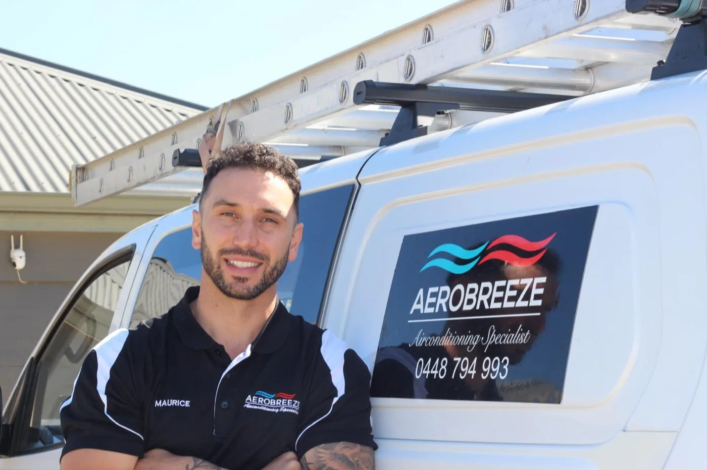 Maurice, owner of Aerobreeze, arms folded beside the signwritten work van with the ladder racked on top