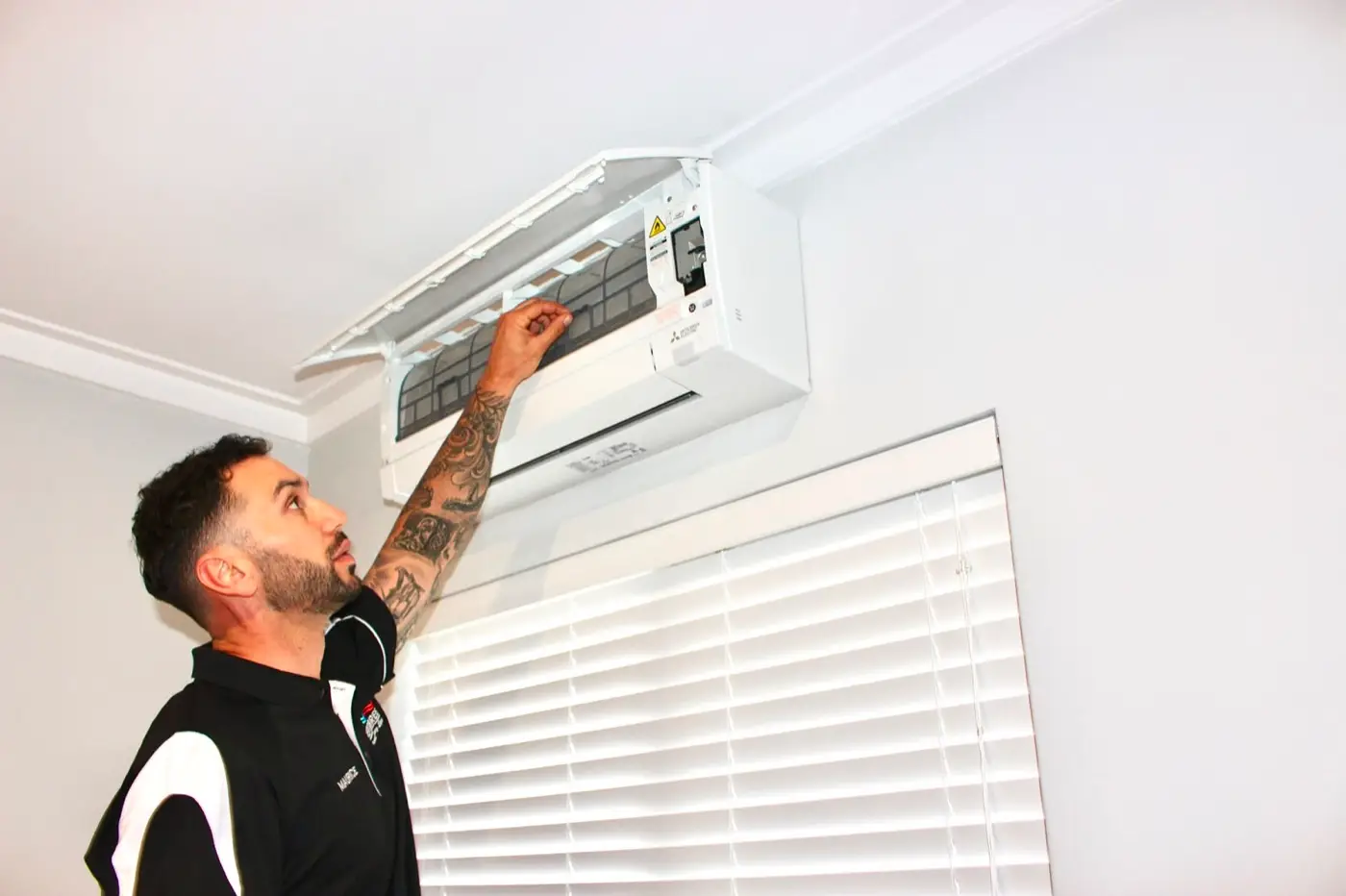 Maurice, owner of Aerobreeze, opening the front of a newly fitted Mitsubishi wall split system indoors