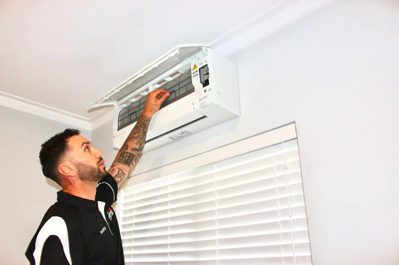 Maurice, owner of Aerobreeze, opening the front of a newly fitted Mitsubishi wall split system indoors
